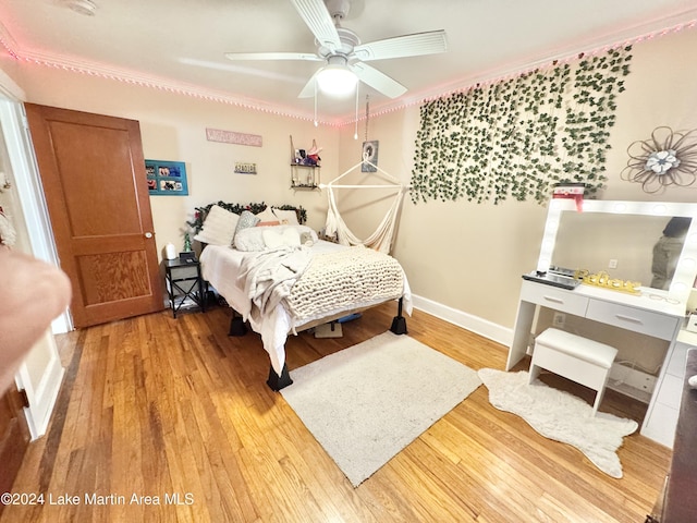 bedroom featuring light hardwood / wood-style flooring, ceiling fan, and ornamental molding