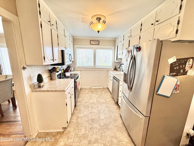 kitchen featuring white cabinets, crown molding, appliances with stainless steel finishes, and tasteful backsplash