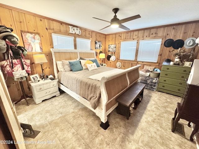 bedroom with ceiling fan, crown molding, and wood walls