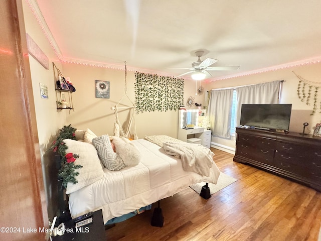 bedroom with hardwood / wood-style flooring, ceiling fan, and ornamental molding