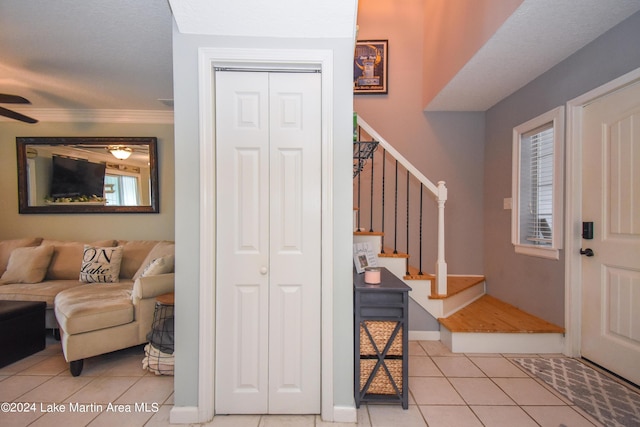 tiled entryway with crown molding and ceiling fan