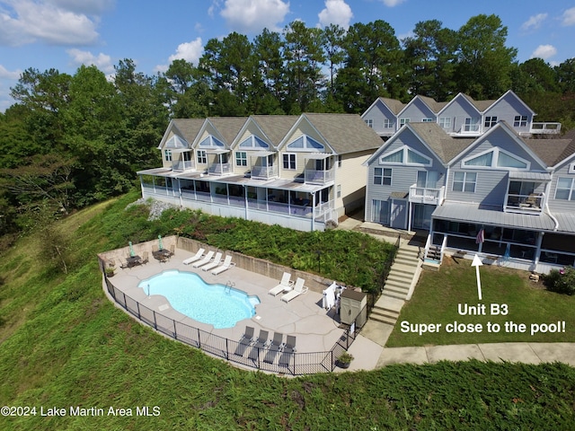 rear view of house with a fenced in pool and a patio