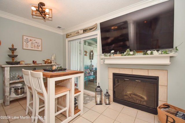 dining area with light tile patterned flooring, a textured ceiling, crown molding, and a tiled fireplace