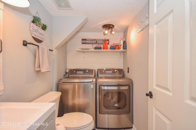 laundry area with washing machine and clothes dryer and a textured ceiling