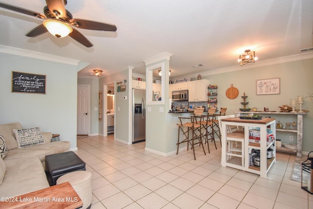 tiled living room with crown molding and ceiling fan with notable chandelier