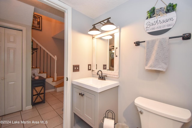 bathroom featuring tile patterned flooring, vanity, toilet, and a textured ceiling