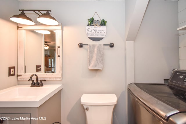 bathroom featuring ceiling fan, toilet, vanity, and washer / dryer