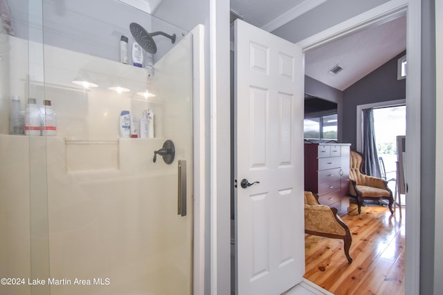 bathroom featuring vaulted ceiling, crown molding, hardwood / wood-style floors, and an enclosed shower