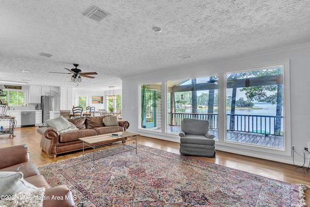 195 Honeysuckle Hl, Tallassee, AL 36078 - living room featuring ceiling fan, a textured ceiling, light wood-style floors, a water view, and crown molding