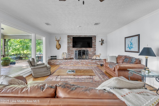 195 Honeysuckle Hl, Tallassee, AL 36078 - living room with wood finished floors, ornamental molding, a fireplace, and a textured ceiling