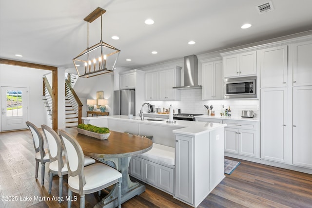 20 Heart Pine Ln, Dadeville, AL 36853 - kitchen with wall chimney range hood, stainless steel appliances, light countertops, decorative backsplash, and a kitchen island with sink