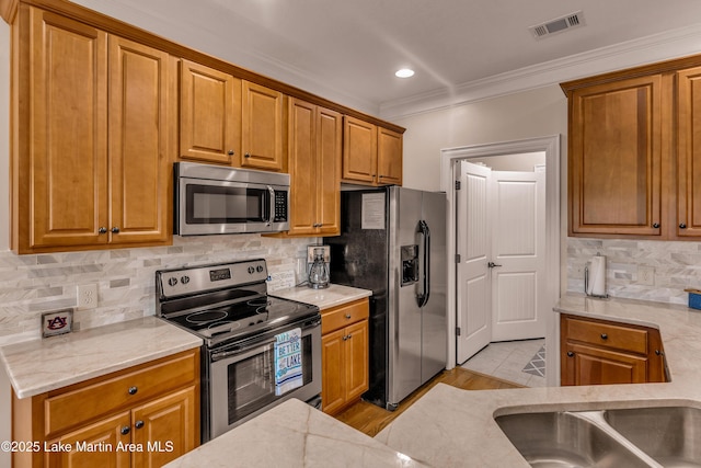 48 Stoneview Summit Ct Unit 2401, Dadeville, AL 36853 - kitchen with appliances with stainless steel finishes, crown molding, backsplash, brown cabinets, and light stone counters