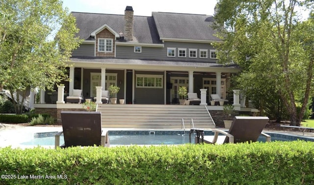 back of house with a chimney and an outdoor pool