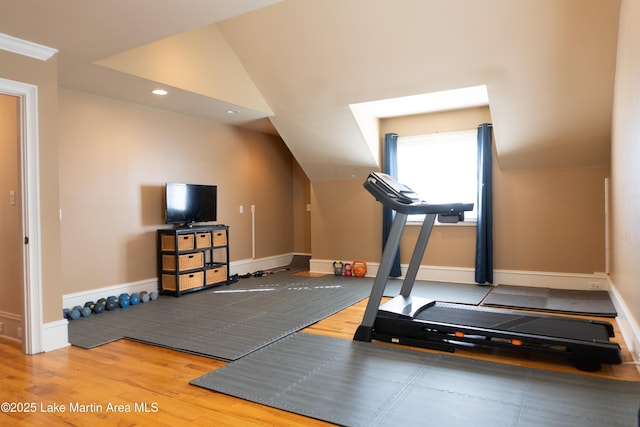 workout room with baseboards, vaulted ceiling, and wood finished floors