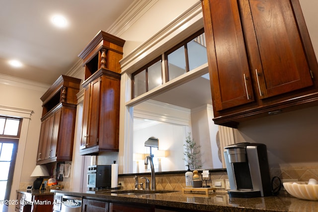kitchen featuring recessed lighting, ornamental molding, a sink, and dark stone countertops