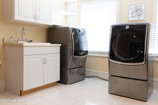 laundry area featuring cabinet space, a sink, a wealth of natural light, and washer and clothes dryer