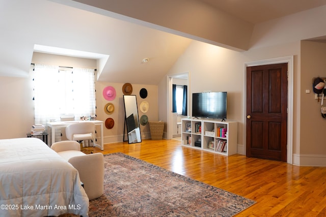 bedroom with baseboards, wood finished floors, and lofted ceiling