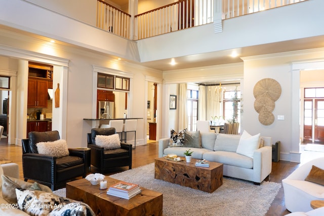 living room with baseboards, ornamental molding, a towering ceiling, and wood finished floors