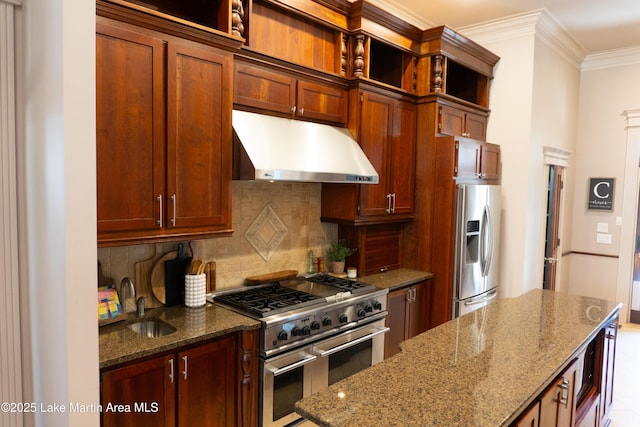 kitchen featuring crown molding, dark stone counters, under cabinet range hood, a sink, and stainless steel appliances