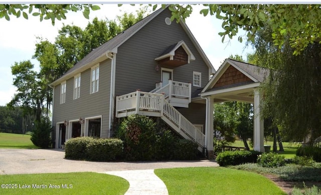 view of front of property with an attached garage, stairs, driveway, and a front yard