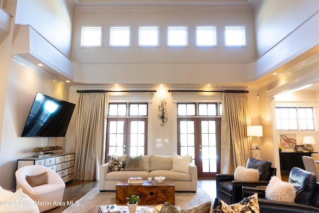 living area featuring ornamental molding, a towering ceiling, and wood finished floors