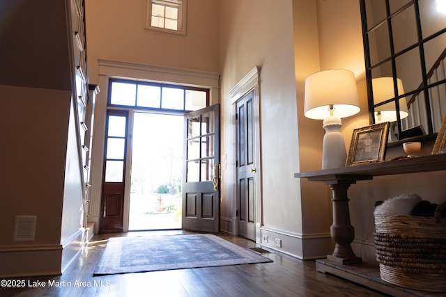 entryway with baseboards, a towering ceiling, wood finished floors, and visible vents