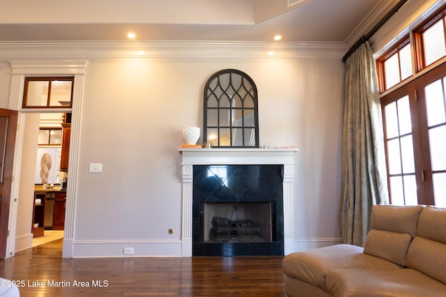 living area with dark wood finished floors, a tile fireplace, baseboards, ornamental molding, and recessed lighting