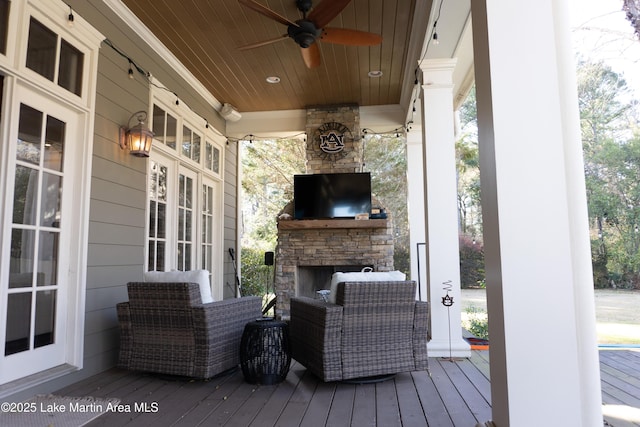 wooden deck featuring a ceiling fan and an outdoor stone fireplace