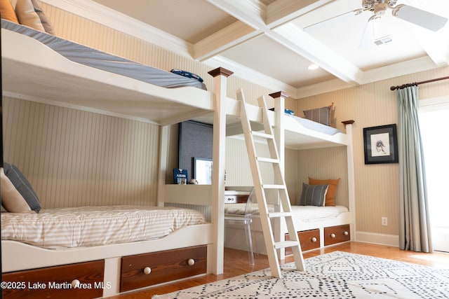 bedroom featuring baseboards, ornamental molding, beamed ceiling, and wood finished floors
