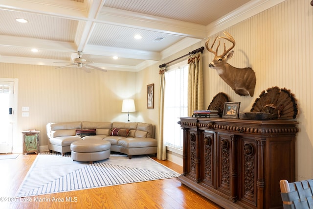 living area with ceiling fan, wood finished floors, beamed ceiling, ornamental molding, and coffered ceiling