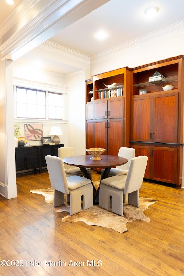 dining space featuring ornamental molding and light wood-style flooring