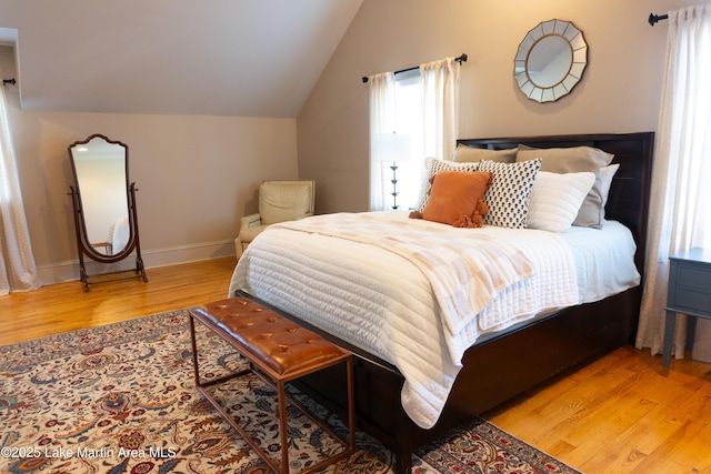 bedroom featuring baseboards, vaulted ceiling, and wood finished floors