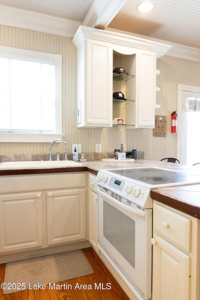 kitchen featuring crown molding, open shelves, a sink, light wood finished floors, and electric stove