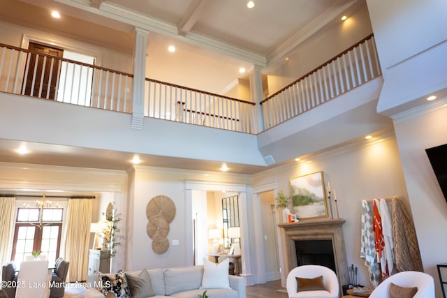 living room with crown molding, an inviting chandelier, a fireplace, recessed lighting, and decorative columns