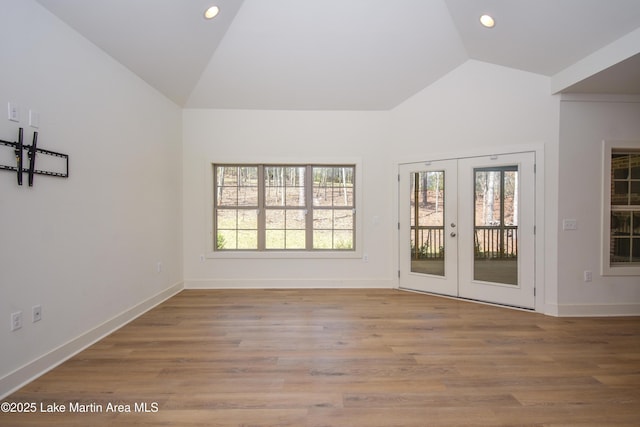 interior space with baseboards, vaulted ceiling, recessed lighting, french doors, and wood finished floors
