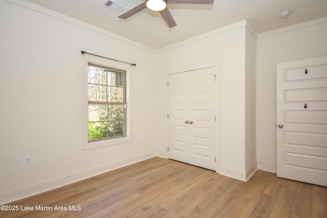 unfurnished bedroom with a closet, visible vents, light wood-type flooring, and baseboards