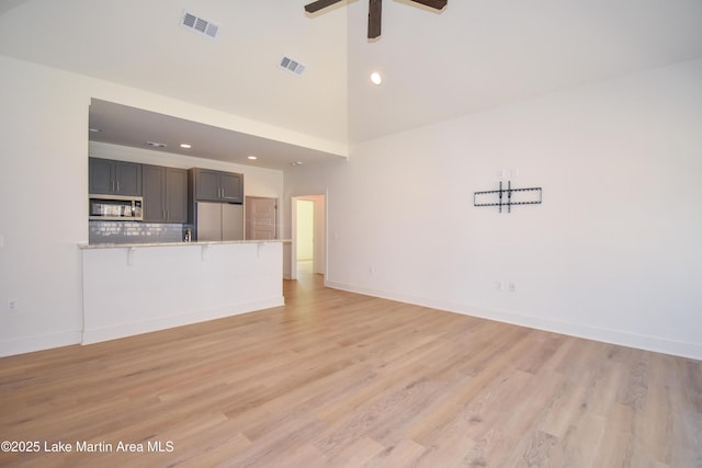 unfurnished living room with light wood-style floors, visible vents, and a ceiling fan