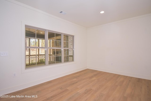 spare room with light wood-style flooring, baseboards, ornamental molding, and visible vents