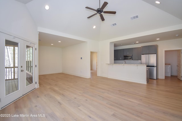 unfurnished living room with high vaulted ceiling, washer / clothes dryer, and visible vents