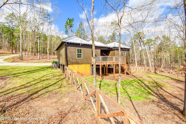 rear view of property with central AC unit, a deck, metal roof, a lawn, and stairs