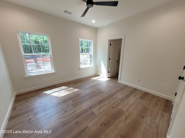unfurnished room featuring light wood finished floors, visible vents, a ceiling fan, and baseboards