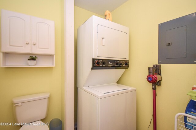 clothes washing area featuring electric panel and stacked washer / drying machine