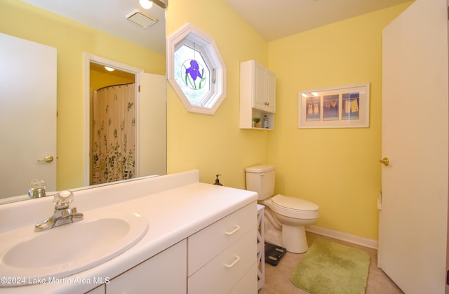 bathroom with toilet, vanity, and tile patterned floors