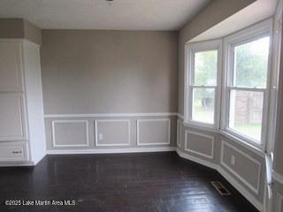 1415 Lee Road 219, Phenix City, AL 36870 - spare room with a decorative wall, wainscoting, and dark wood-style flooring