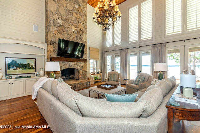 living room with dark hardwood / wood-style flooring, a stone fireplace, french doors, and a healthy amount of sunlight