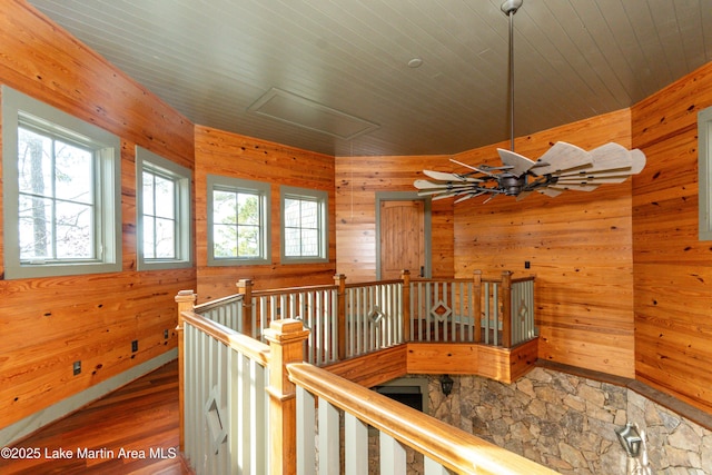 hallway with wooden walls, hardwood / wood-style floors, and a wealth of natural light