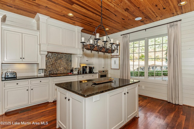 kitchen with hanging light fixtures, dark stone counters, and white cabinets