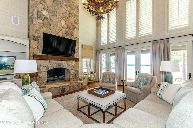 living room with french doors, a stone fireplace, hardwood / wood-style flooring, and a wealth of natural light