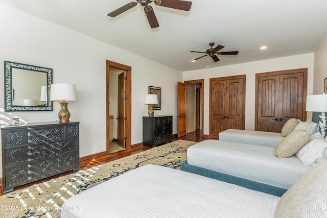 bedroom featuring multiple closets, wood-type flooring, and ceiling fan