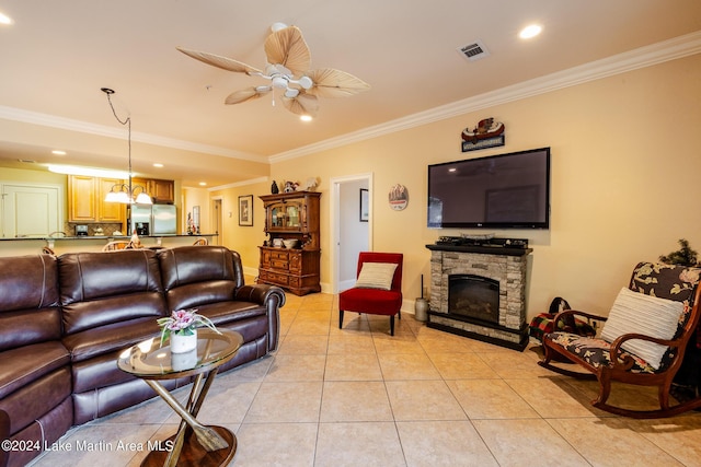 living room with ceiling fan, light tile patterned flooring, a stone fireplace, and crown molding